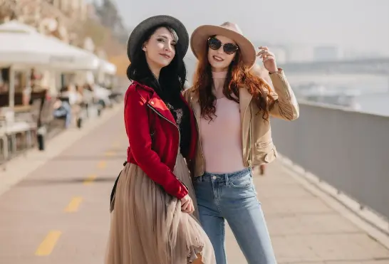 Two women wearing stylish designer jackets and hats representing luxury fashion trends from FARFETCH Hong Kong